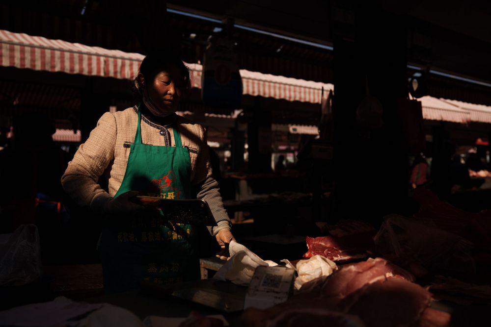 Market vendor in an apron working at a stall in dark atmospheric lighting.