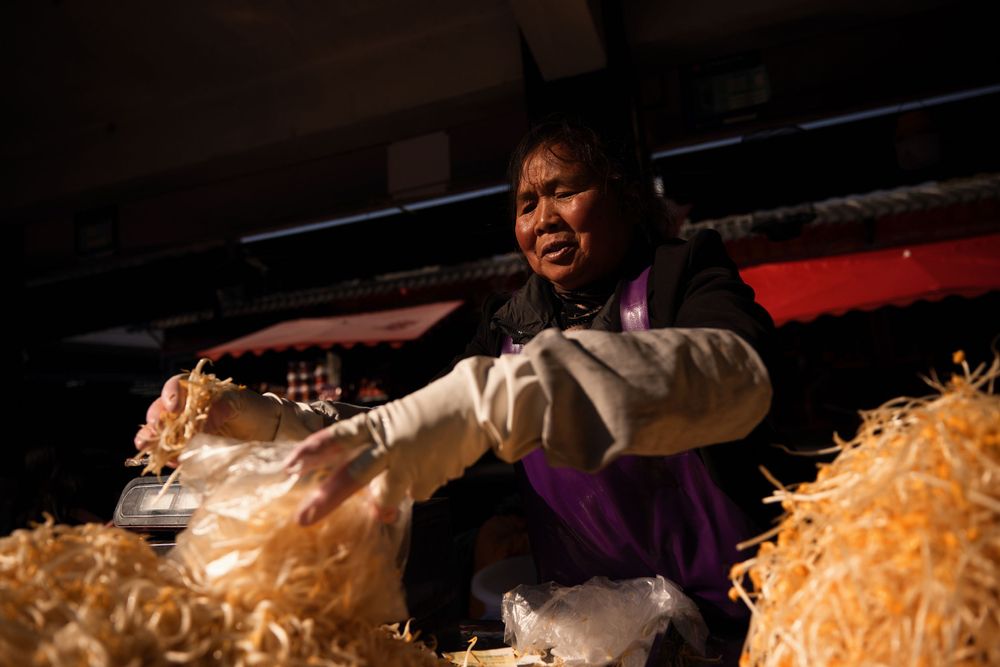 Worker sorting and processing straw or hay material at an indoor facility.