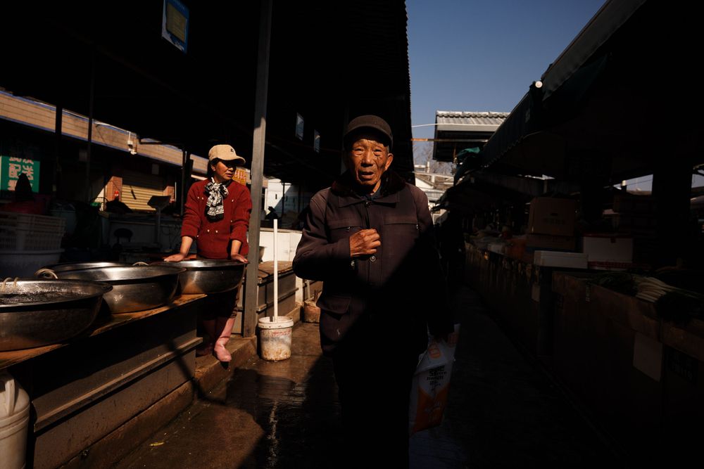 Market vendors work in the early morning hours at an outdoor Japanese marketplace in shadows and dim lighting.