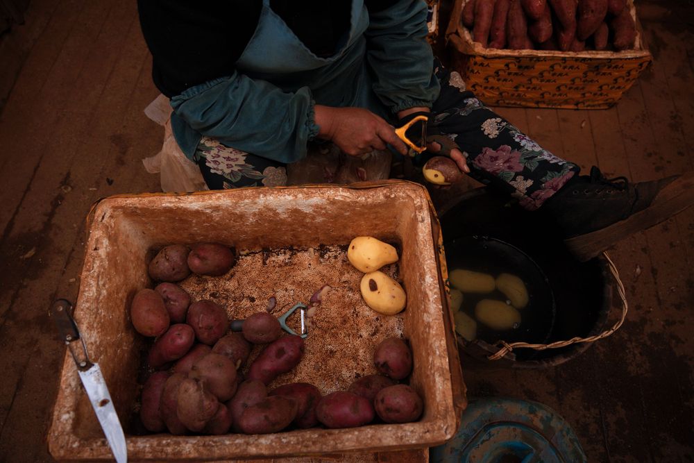 Overhead view of red potatoes in a rustic wooden crate with someone kneeling nearby.