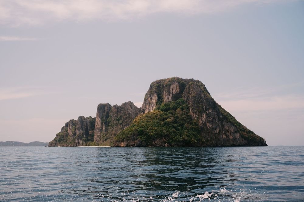 Scenic view of rocky coastal cliffs rising from blue ocean waters under a cloudy sky.