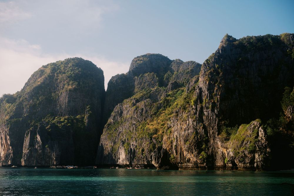 Panoramic view of towering limestone cliffs and turquoise waters in a tropical bay under clear blue skies.