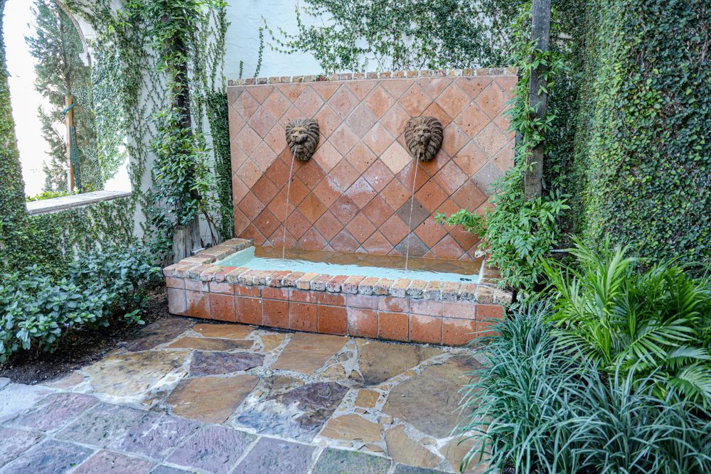 Stone patio with ivy-covered walls and decorative outdoor lighting fixtures.