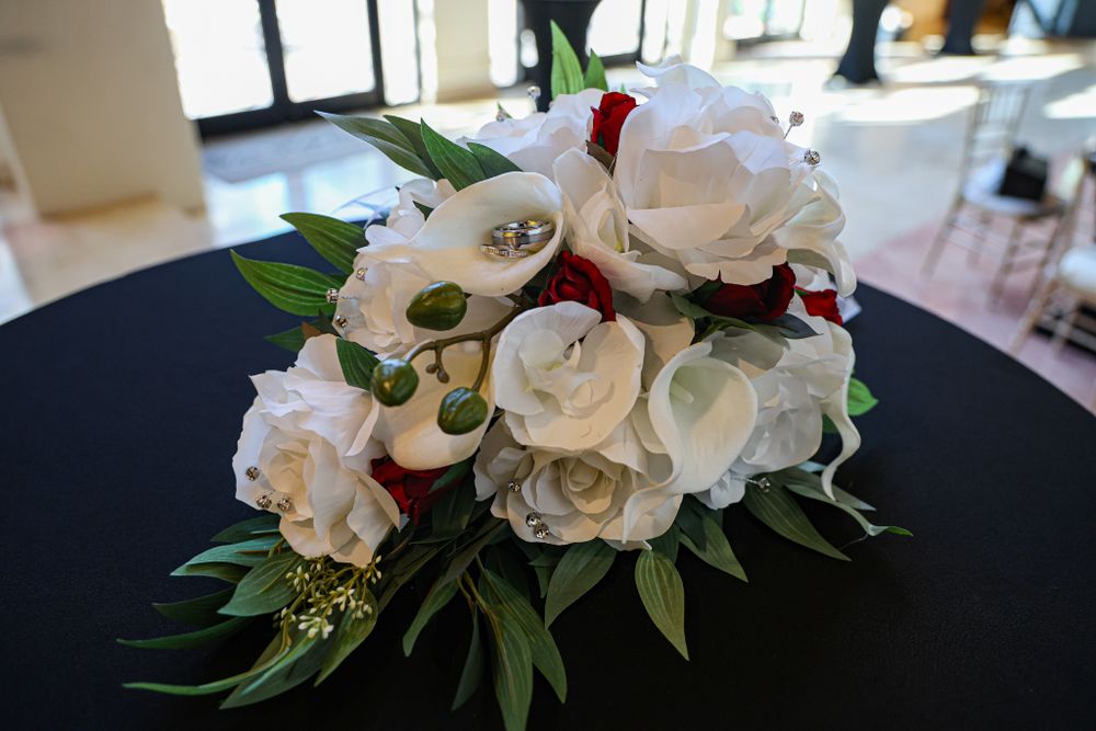Elegant white rose bouquet with greenery arranged on dark background.