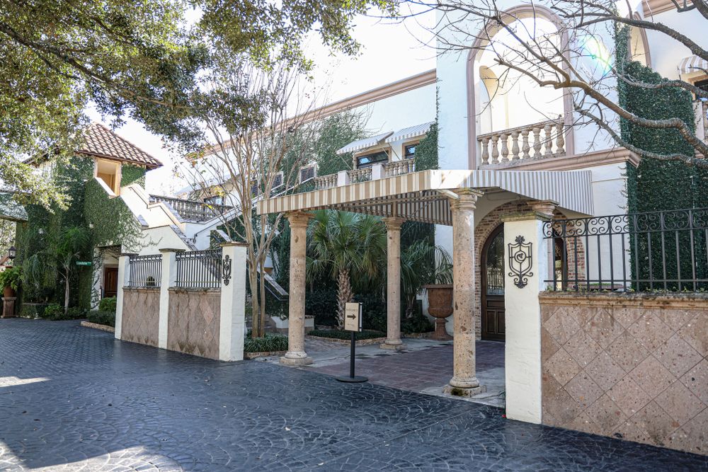 Elegant outdoor walkway with white columns and archways in a Mediterranean style.