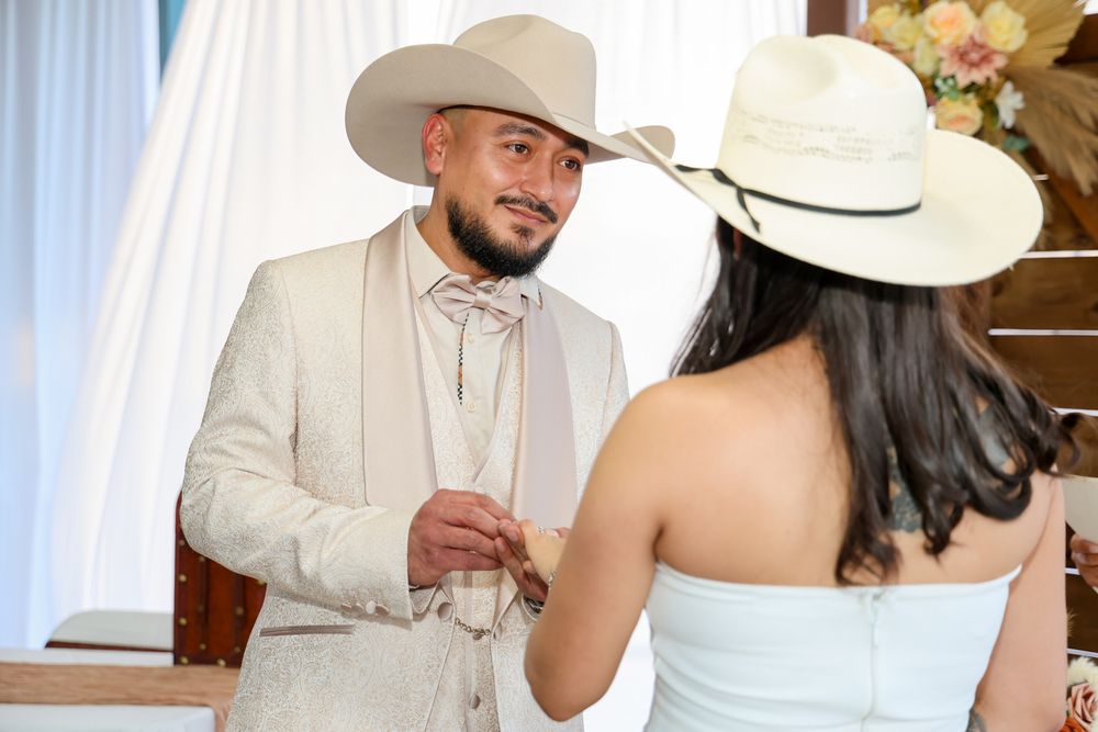 A wedding couple shares a tender moment during their reception in a light-filled venue with white decor.