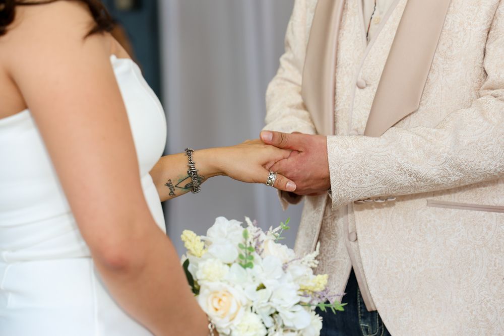 Elegant wedding party in blush pink dresses holds delicate white and yellow floral bouquets.