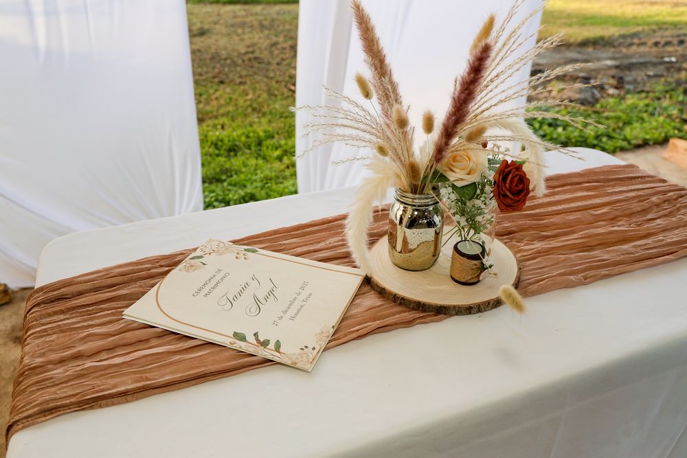 Rustic wooden table decorated with dried pampas grass and vintage decor elements for an outdoor event.