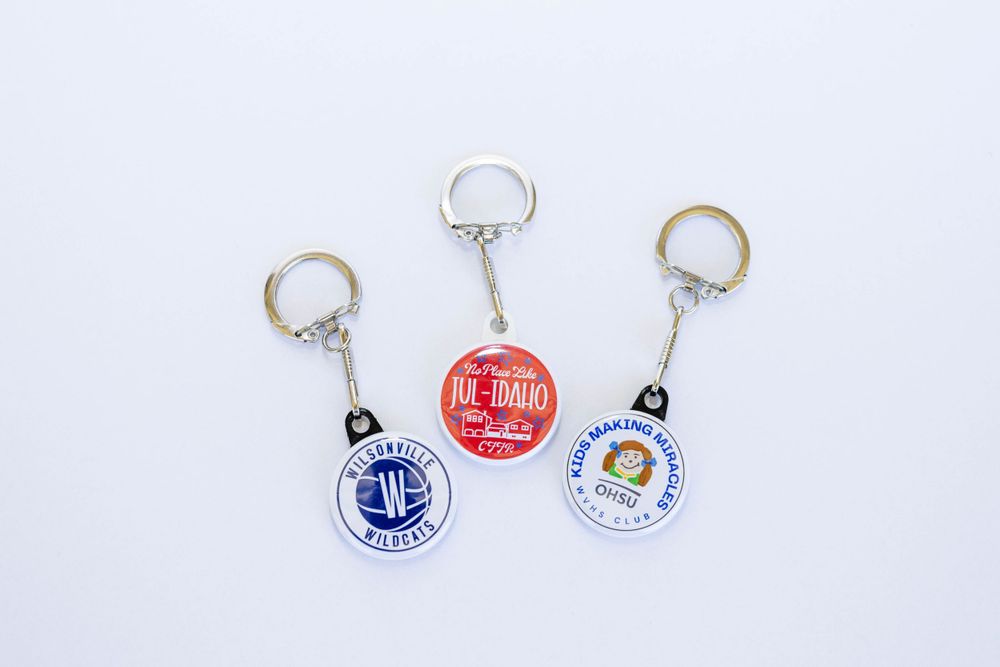 Three colorful custom logo keychains with metal rings on a white background.
