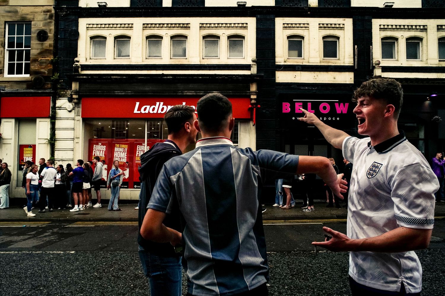 Busy street scene outside Ladbrokes shop with pedestrians walking past.