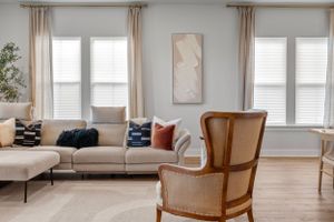 Bright living room with neutral decor, beige sectional and vintage accent chair.