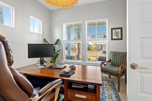 Home office with wooden desk, ergonomic chair and woven pendant light.
