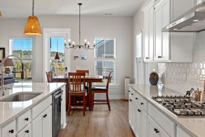 White kitchen with quartz countertops, rattan pendant lights and stainless steel appliances.