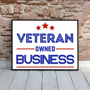 A framed "Veteran Owned Business" sign with three red stars and text in blue against a white background on a stone wall.