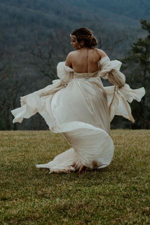 A flowing white wedding dress twirls gracefully against a mountainous backdrop.