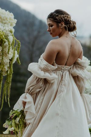 Ethereal wedding dress with billowing sleeves photographed against mountain scenery.