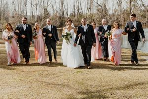 Wedding party walking together on a sunny day with bridesmaids in pink dresses.