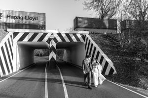 Playful Black and white photo of couple walking through geometric striped tunnel while train moves overhead in south Georgia.