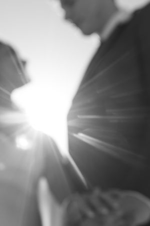 Artistic black and white lens flare creates a dreamy silhouette effect at an outdoor wedding ceremony.