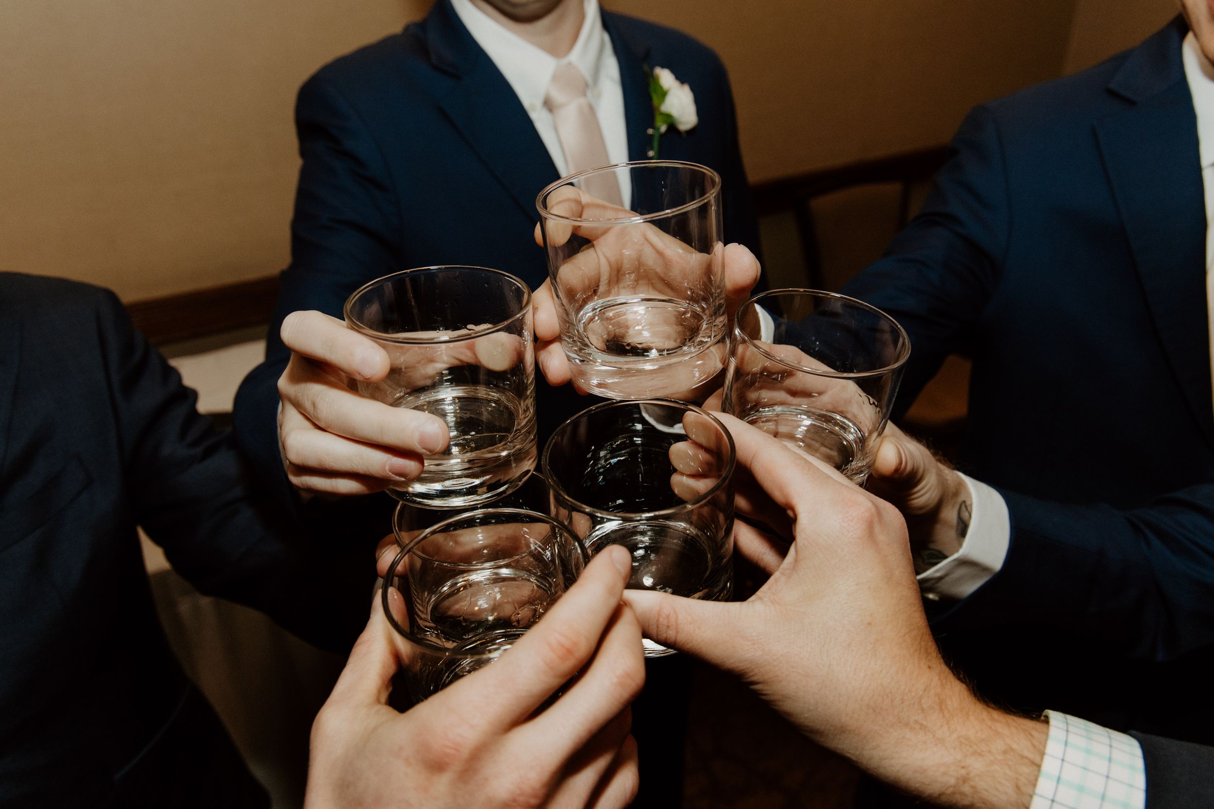 Wedding guests raising glasses in celebratory toast with drinks.