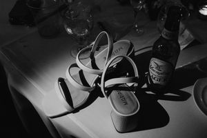 Wedding shoes arranged artistically in dramatic black and white lighting on a table.