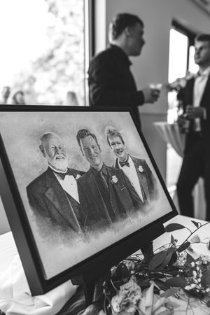 A vintage portrait photo in black and white frame is displayed with guests chatting in the background at an event.