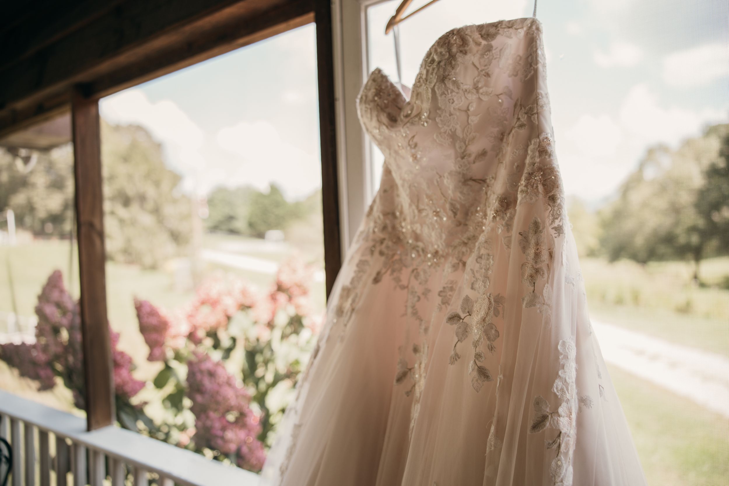 A bride's wedding dress in blush pink hanging on display in a bridal boutique.