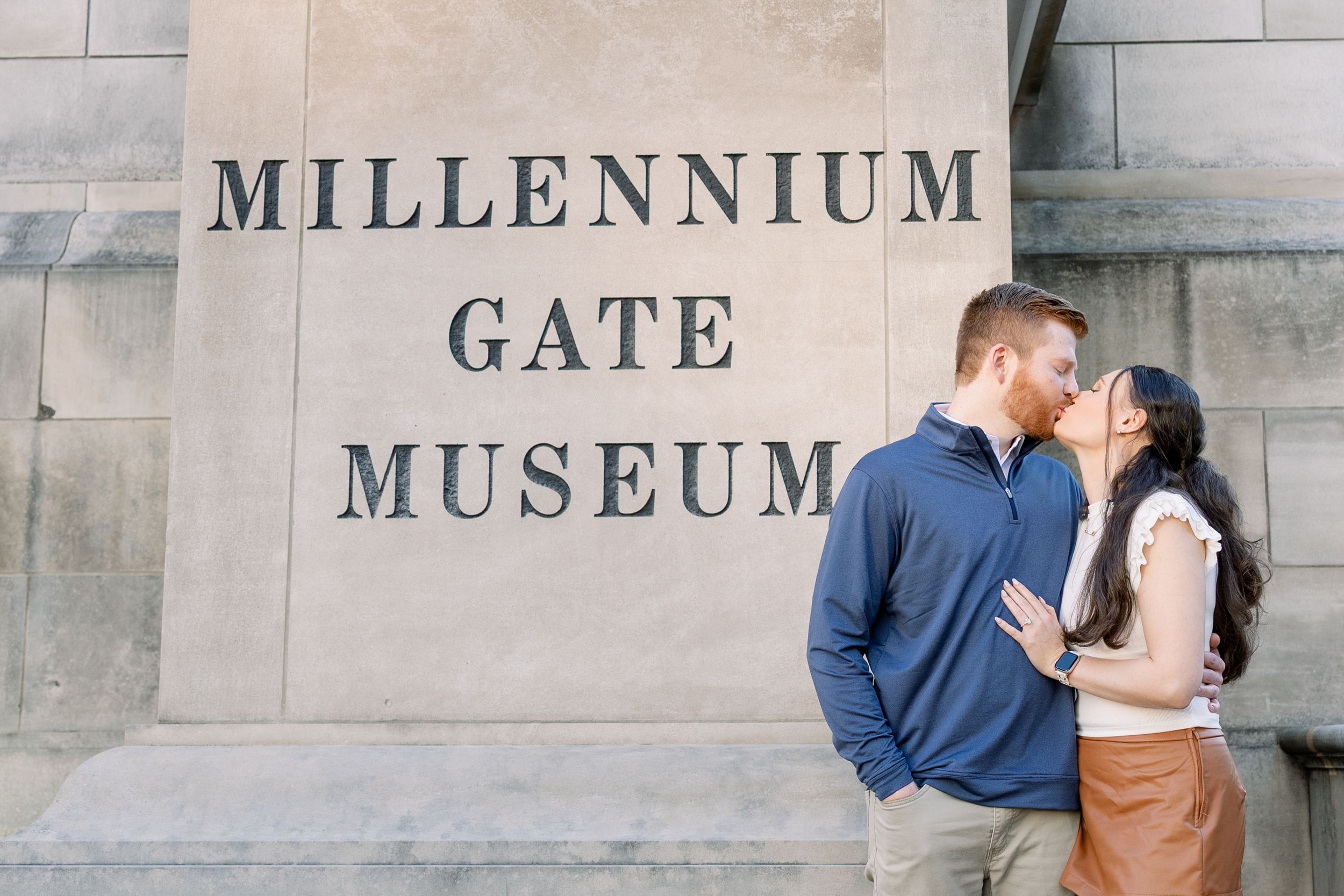 Couple kissing in front of the Millennium Gate Museum stone wall sign in Atlanta.