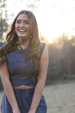 Candid portrait against sunset shows genuine laughter and casual outdoor style.