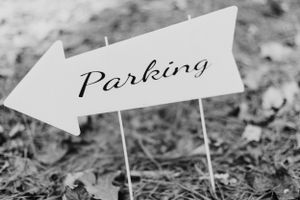 Black and white directional wedding parking arrow sign stuck in ground.