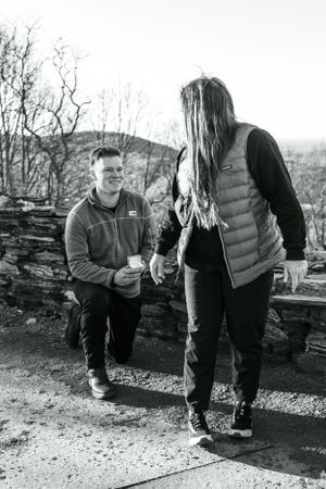 Black and white photograph of a surprise proposal moment on a mountain vista.