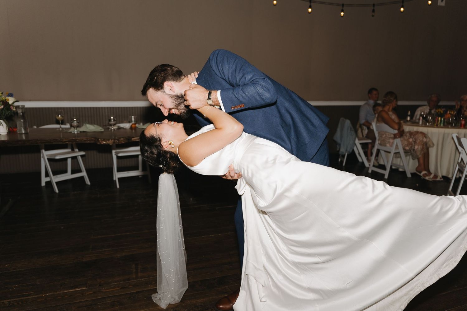 A romantic dip pose during a wedding dance on a dark wooden floor.