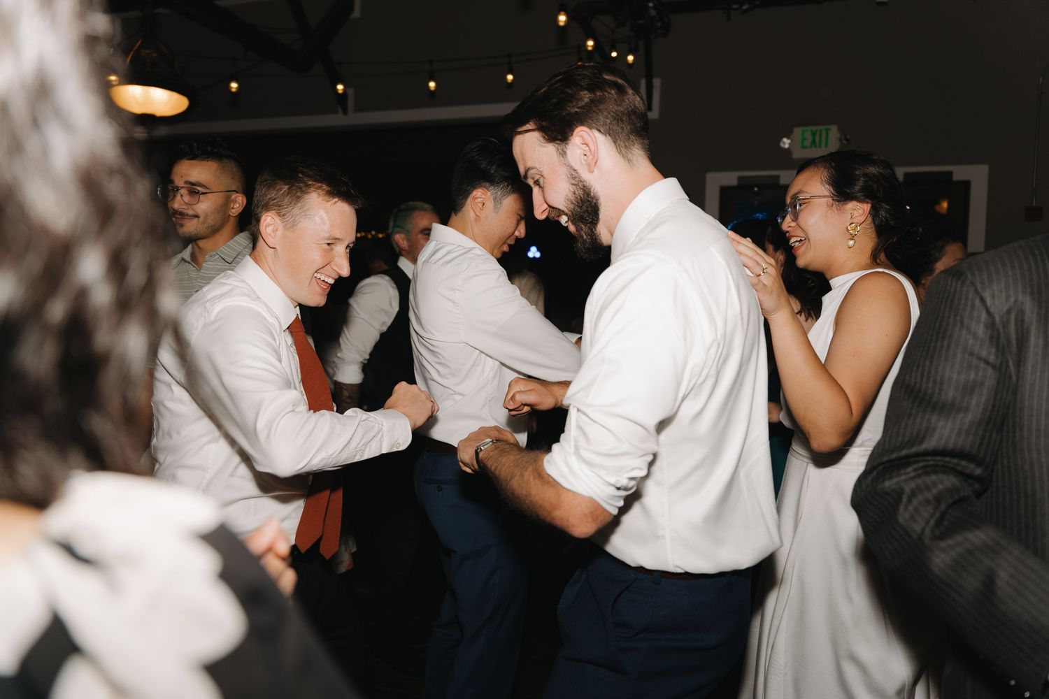 Wedding guests dancing energetically on the dance floor at a reception.