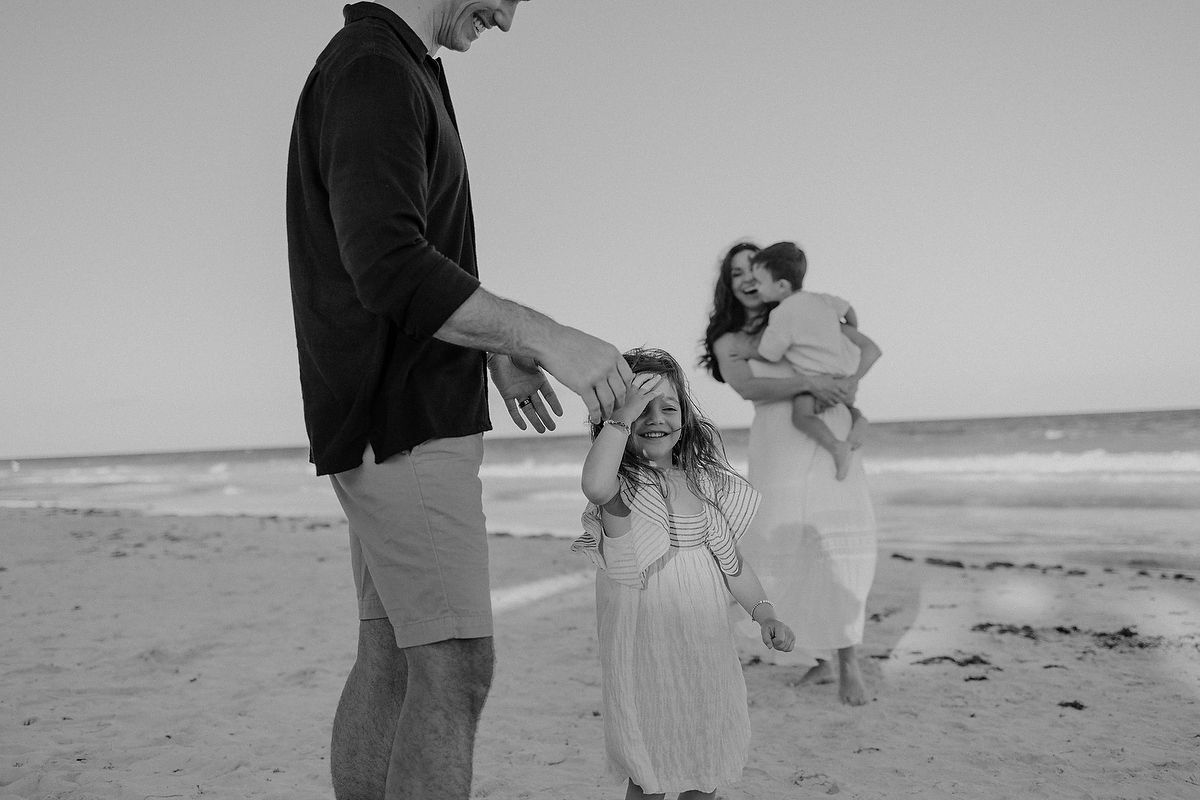 Family running and playing together on the Caribbean beach during luxury vacation photoshoot in Tulum.