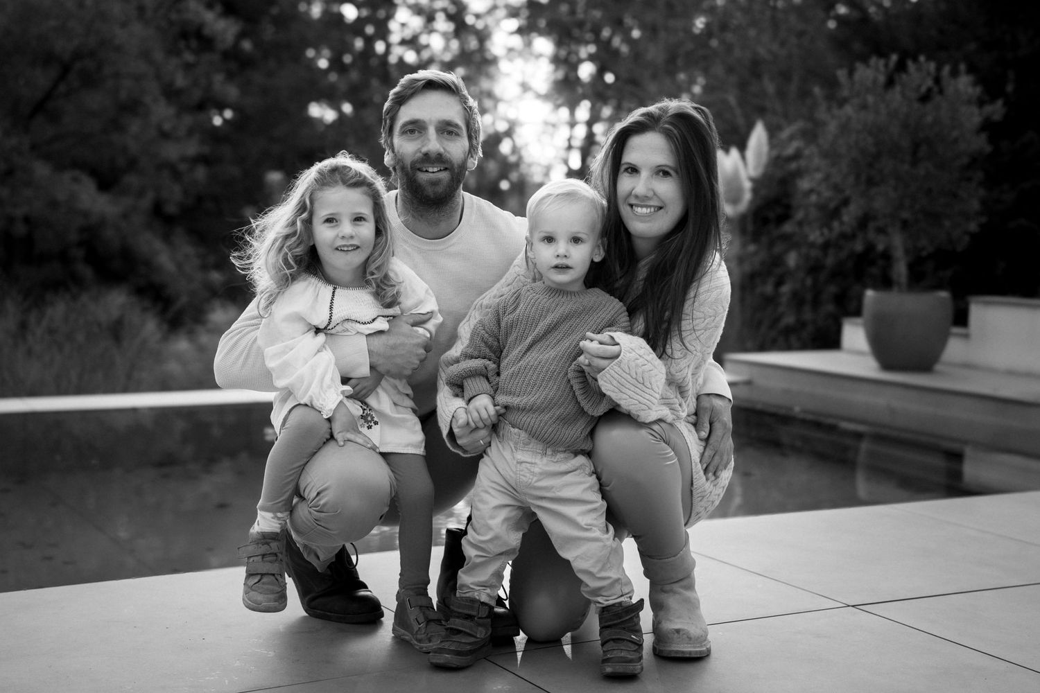 Familienporträtserie, die intime gemeinsame Momente auf einer Terrasse in Schwarzweiß zeigt.