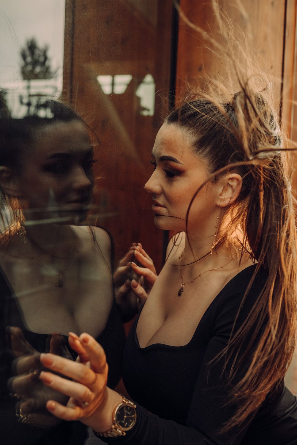 Side profile portrait showing someone applying makeup in warm lighting.