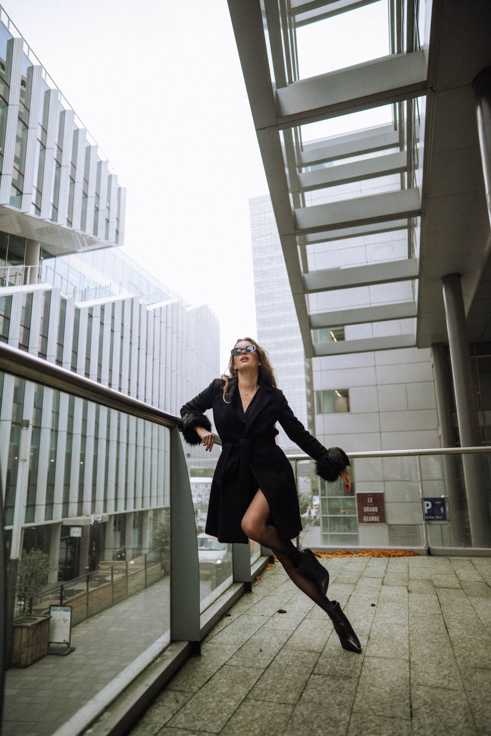 Figure in dark clothing performing dynamic movements in modern architectural setting.