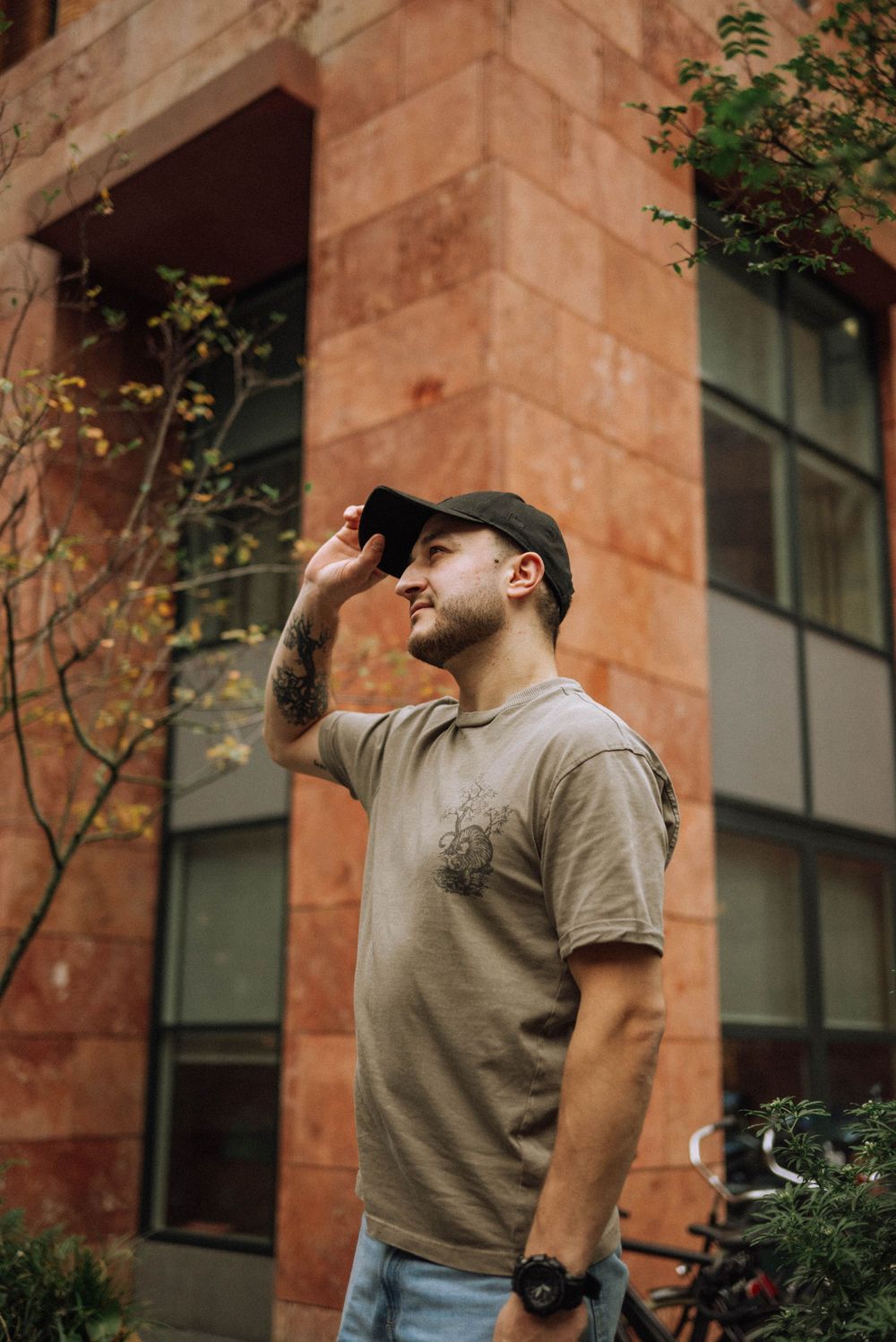 Person in casual attire leaning against terracotta colored building wall.