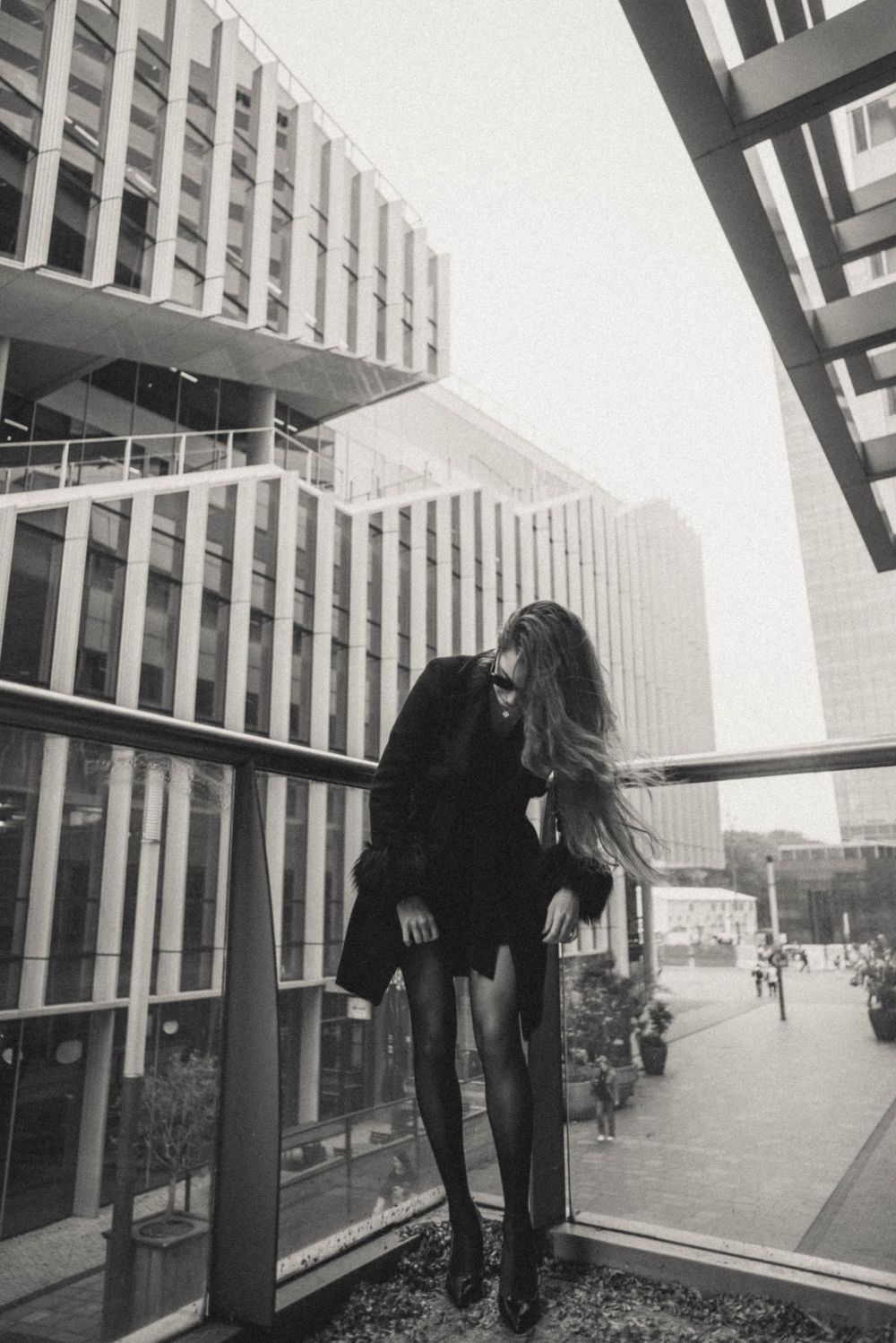 Figure in black moving dynamically against modern glass building exterior.