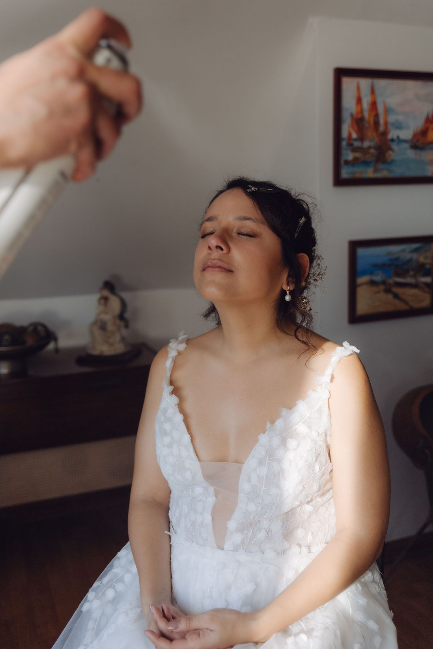 Bride in white wedding gown having makeup setting spray applied during bridal getting ready session.