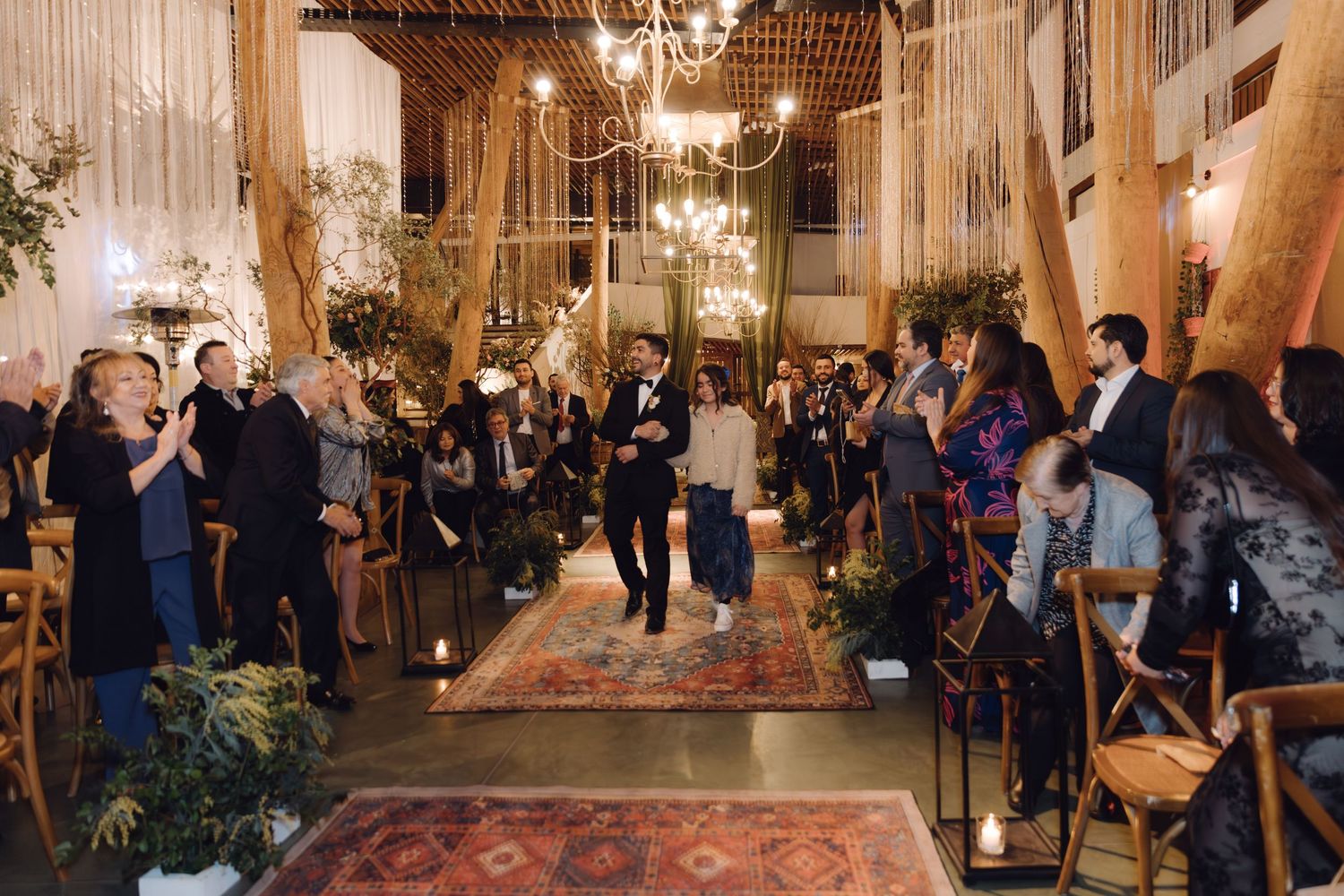 Newlyweds walking back down the aisle as guests applaud at a beautifully decorated wedding.