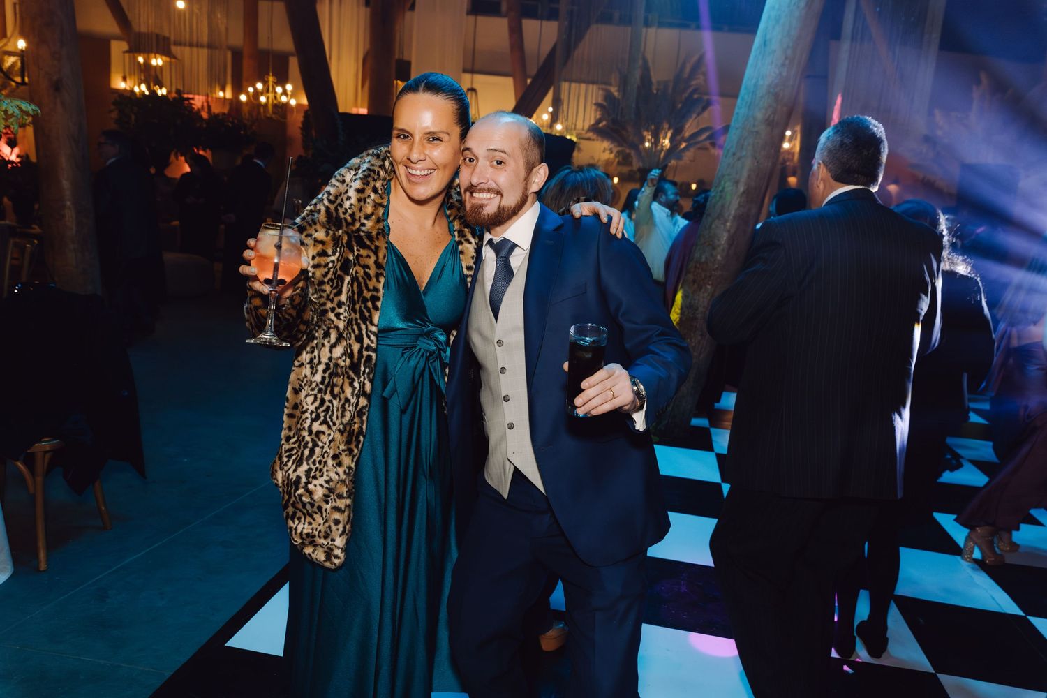 Couple posing and smiling at elegant wedding reception on black and white dance floor.