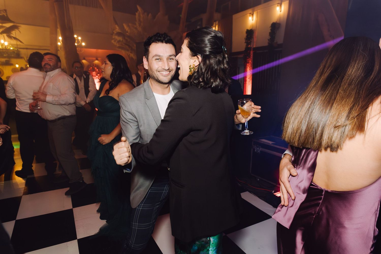 Couple slow dancing together at elegant wedding reception party on checkered floor.