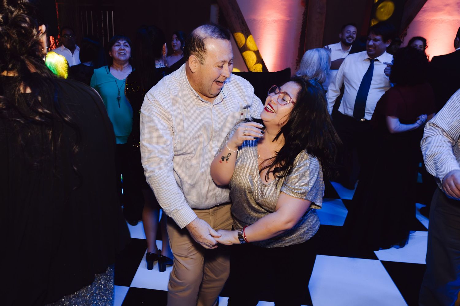 Older couple laughing and dancing together joyfully at lively wedding reception party.