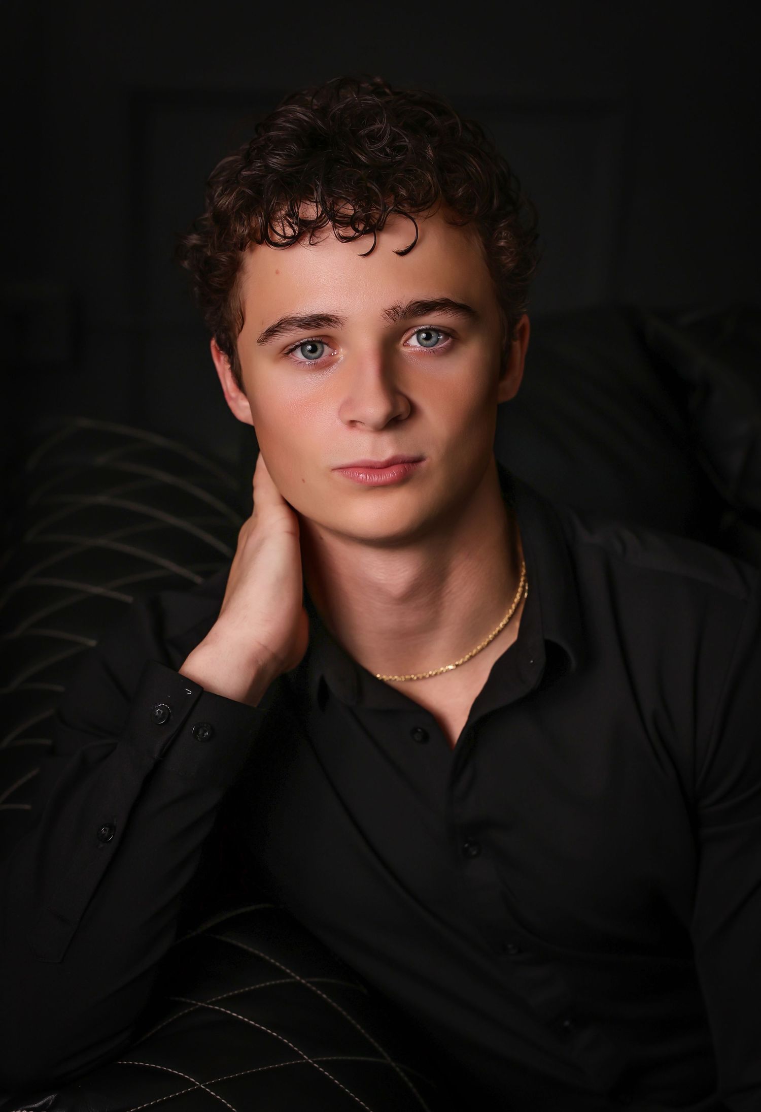 Dramatic studio portrait with moody lighting against dark background.