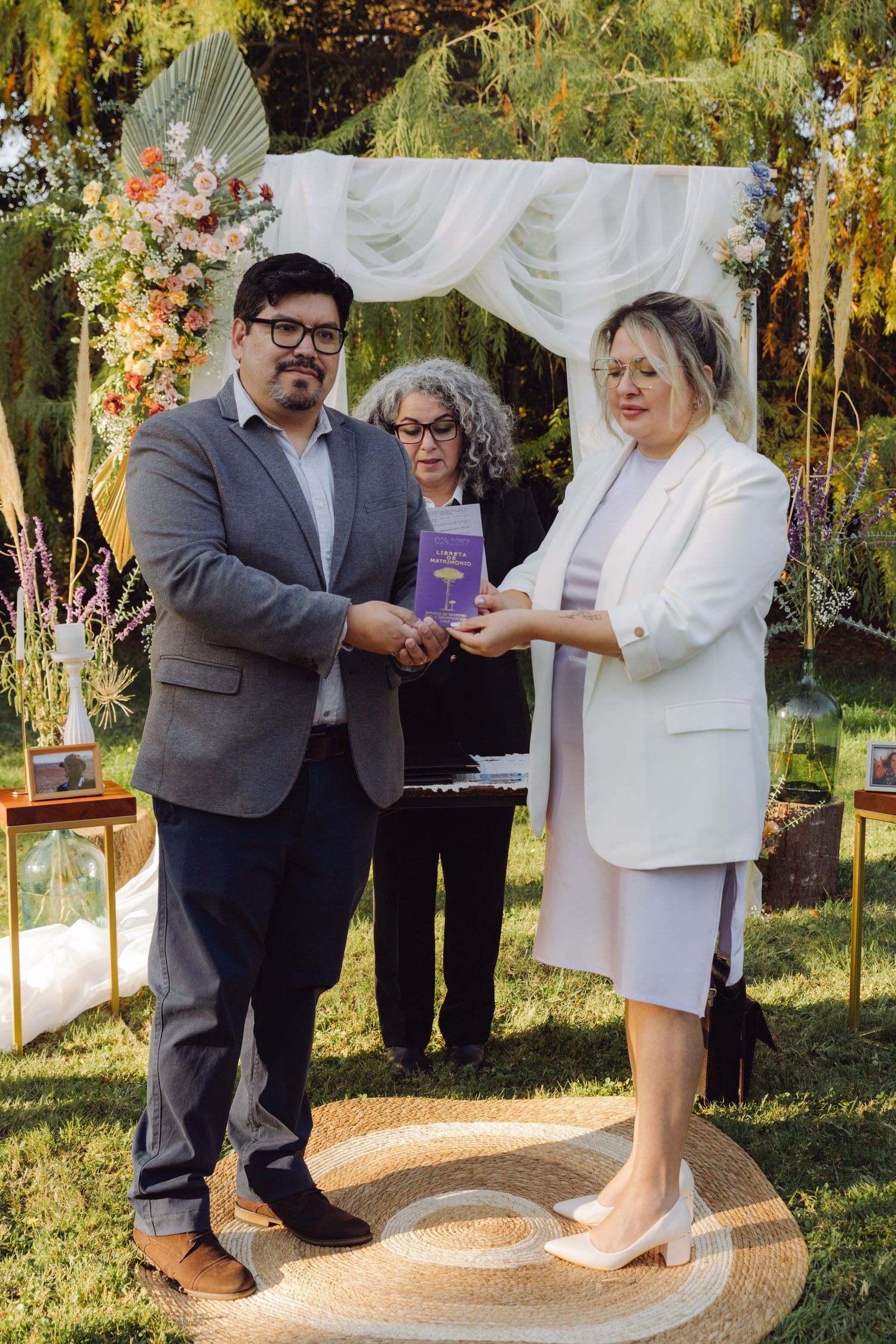 Bride and groom holding purple marriage certificate together at outdoor wedding ceremony.
