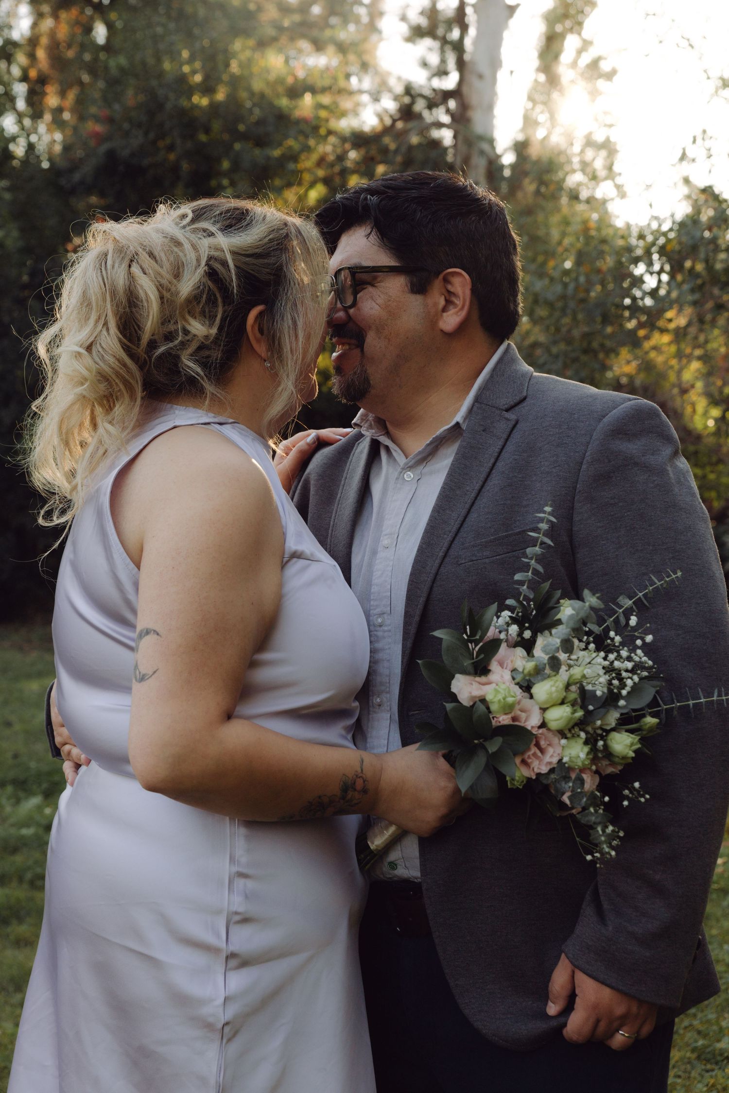 Wedding couple facing each other about to kiss, groom holding pink and white bridal bouquet.