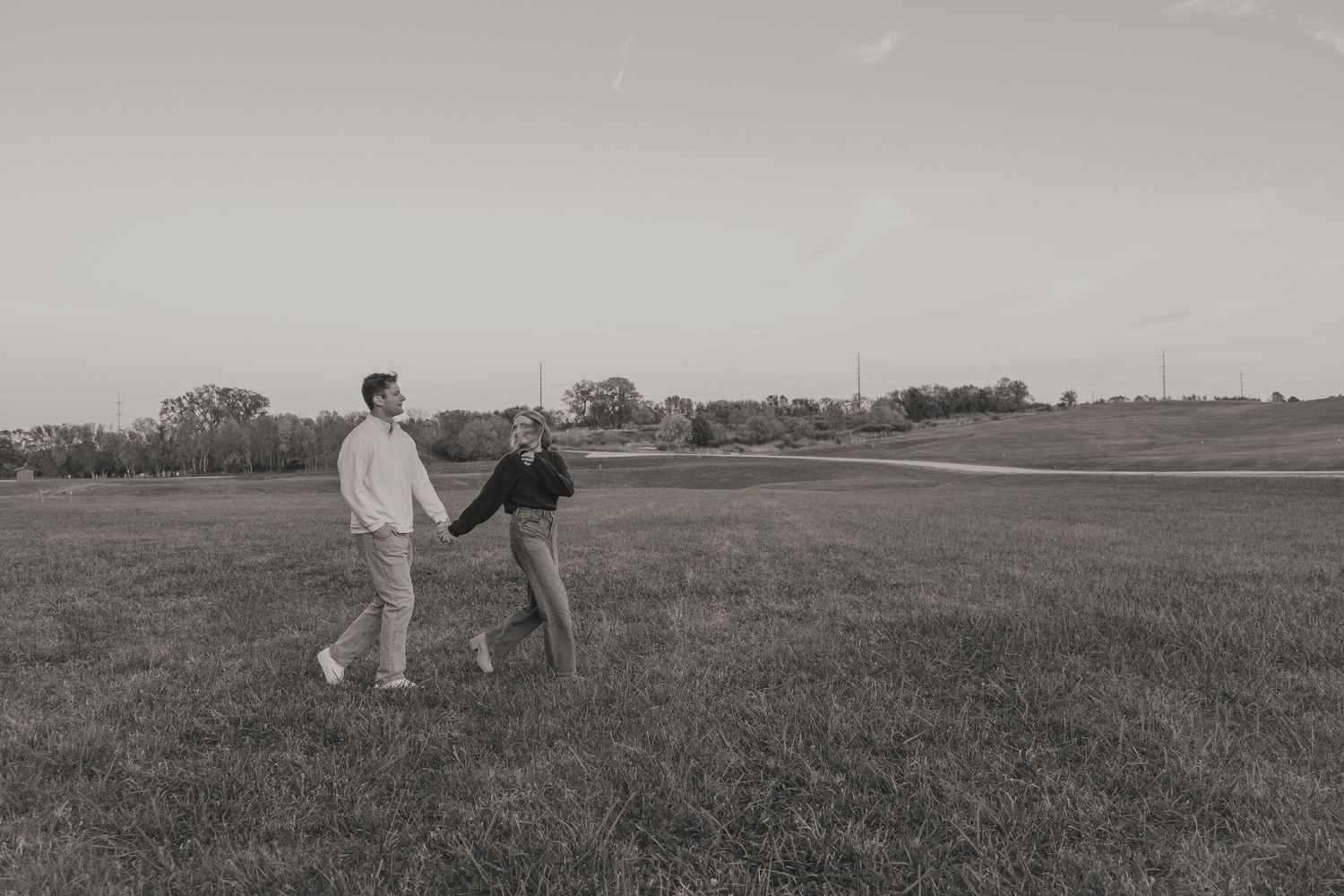 A series of black and white photographs showing people walking through open fields in a rural landscape.