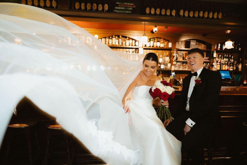 Bride and groom smile as wedding veil billows dramatically inside Hotel Doolin, Co. Clare