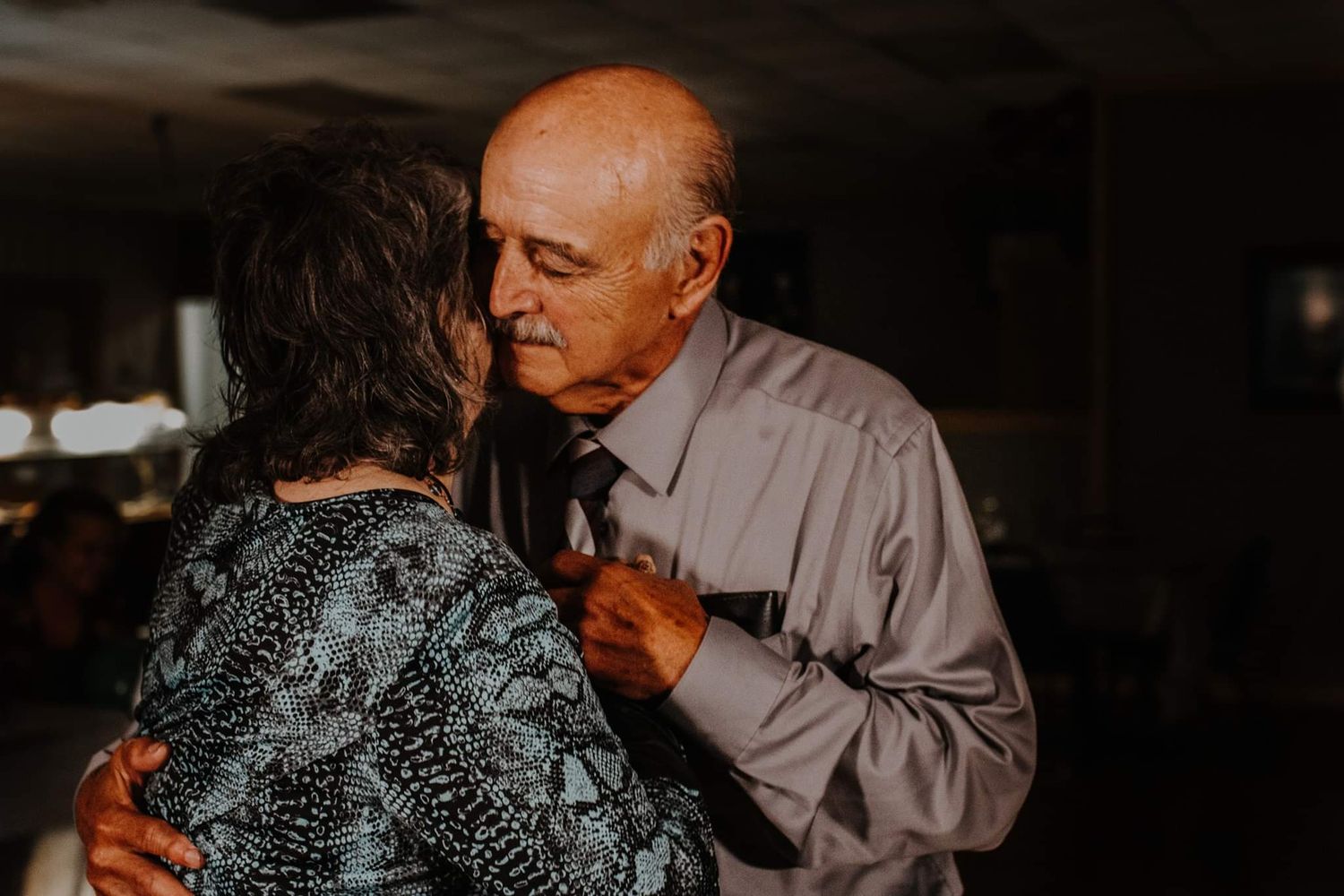 Couple dancing together at a dimly lit reception venue during an intimate celebration.